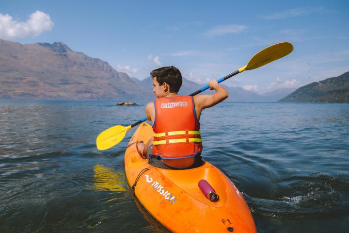 a man holding a yellow frisbee in a body of water