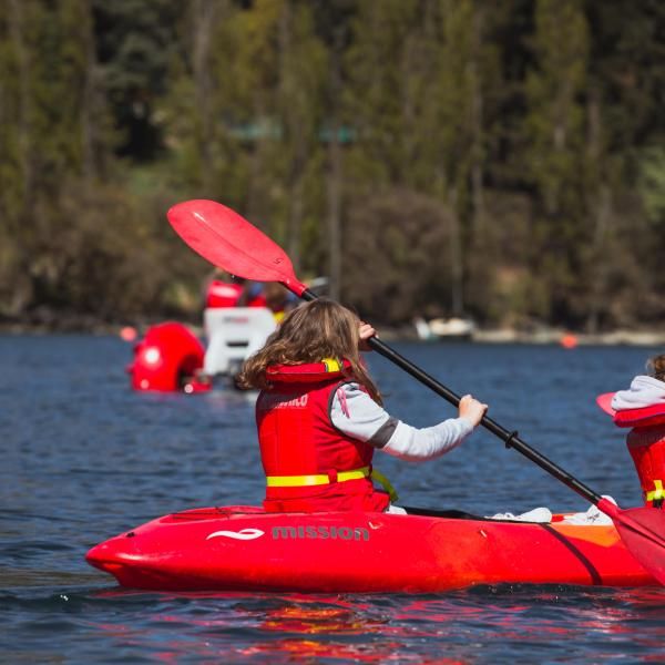 a man riding on the back of a red boat on the water