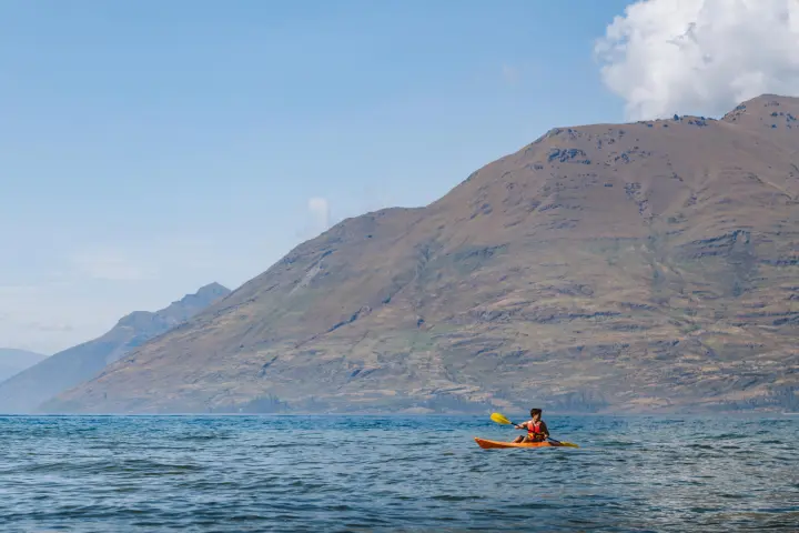 a small boat in a body of water with a mountain in the background